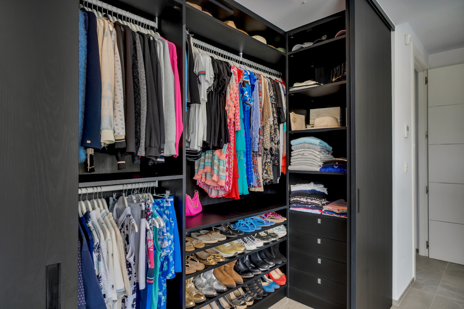 Amplio vestidor con armarios de madera oscura, rieles colgantes integrados, estantes escalonados para zapatos y cajones profundos para una organización óptima.