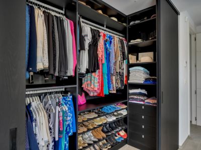 Amplio vestidor con armarios de madera oscura, rieles colgantes integrados, estantes escalonados para zapatos y cajones profundos para una organización óptima.