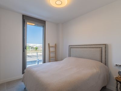 Luminosa habitación con cama, cabecero tapizado con tachuelas y armario empotrado. Gran ventanal con acceso al exterior y suelo de gres.