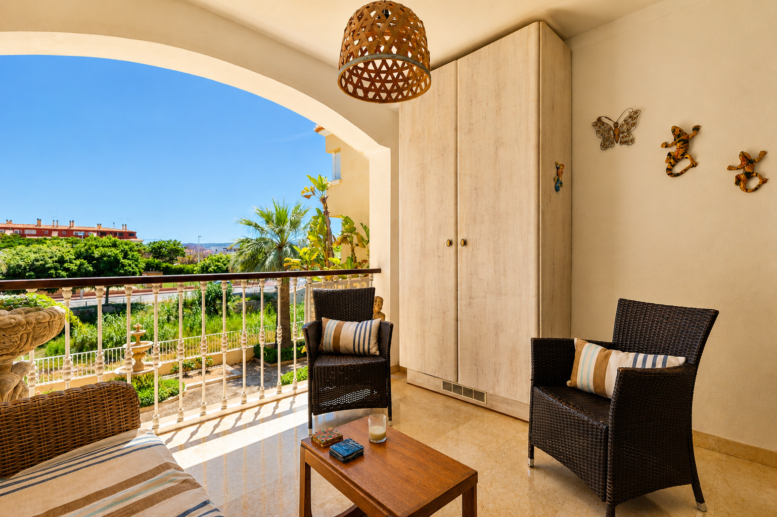 Amplia terraza privada con suelo de mármol, mobiliario de ratán y mesa de madera. Incluye armario empotrado y ofrece vistas a la vegetación y cielo despejado.