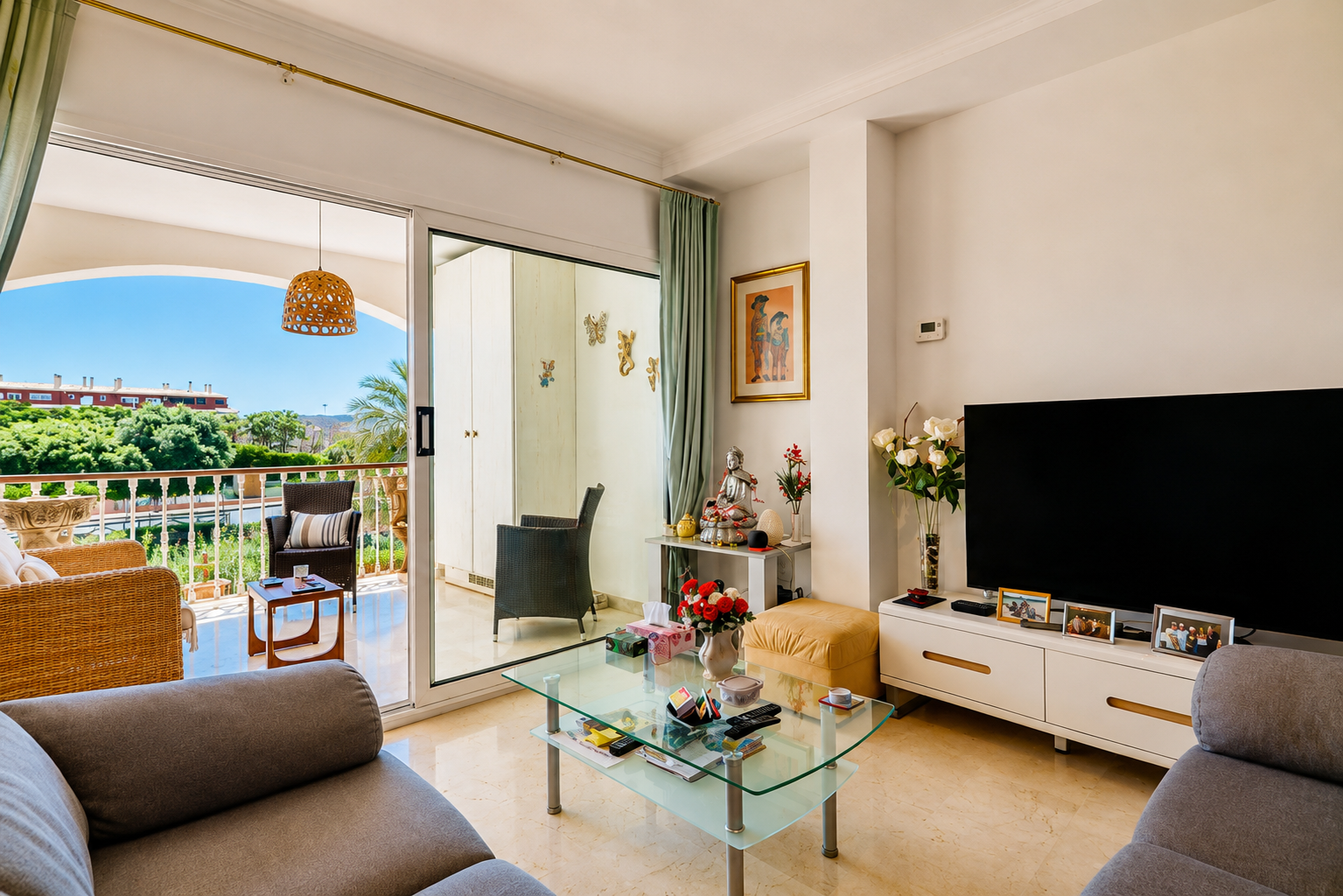 Amplio salón con suelo de mármol y acceso directo a una terraza privada, equipada con mobiliario de mimbre y vistas a la vegetación.