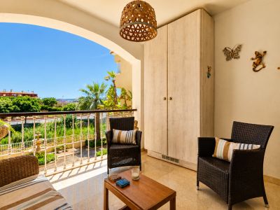 Amplia terraza privada con suelo de mármol, mobiliario de ratán y mesa de madera. Incluye armario empotrado y ofrece vistas a la vegetación y cielo despejado.