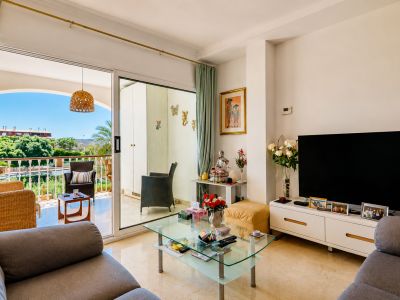 Amplio salón con suelo de mármol y acceso directo a una terraza privada, equipada con mobiliario de mimbre y vistas a la vegetación.