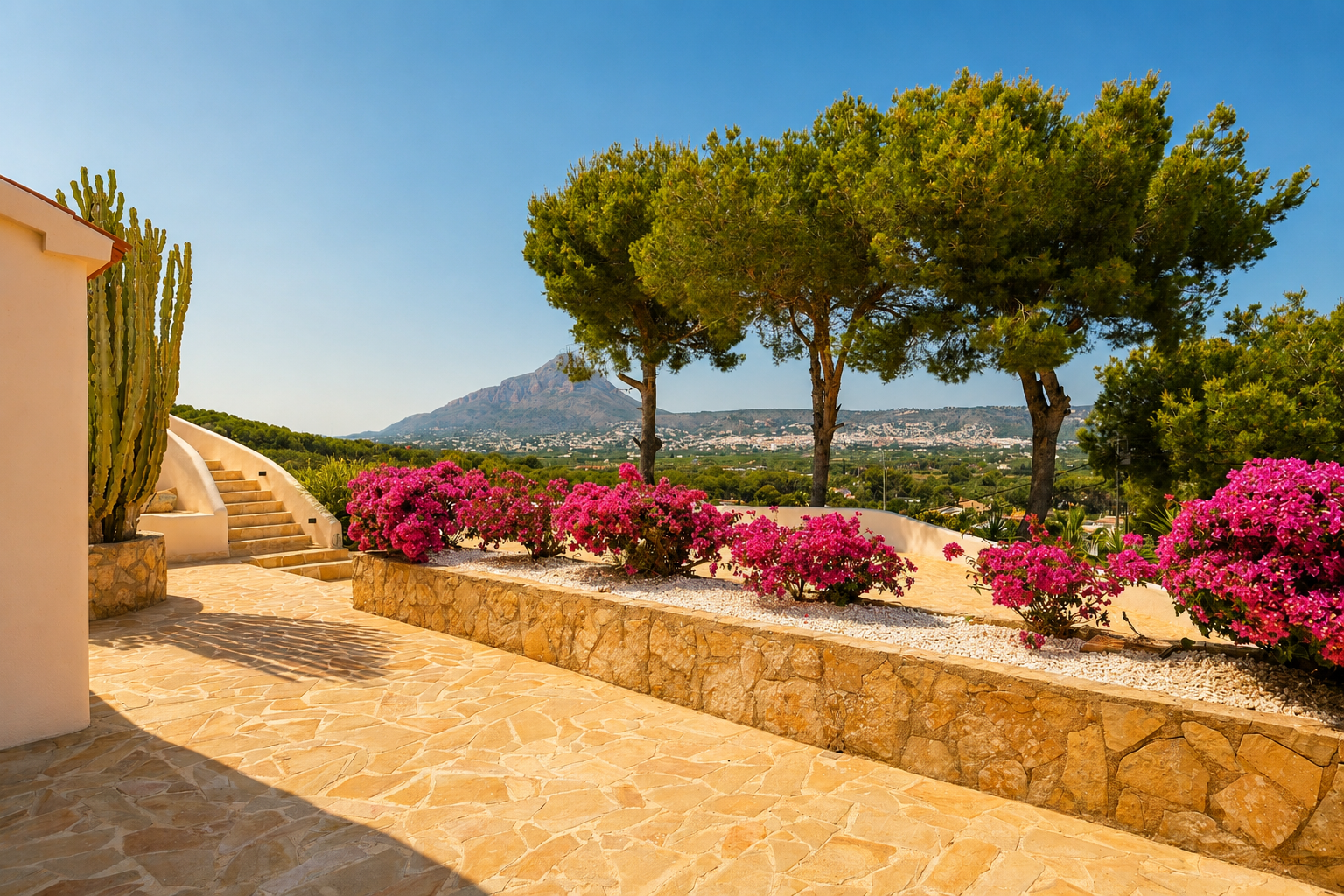 Terraza exterior con pavimento de piedra natural, escalera curva, y vibrantes buganvillas. Incluye un gran cactus y vistas panorámicas a las montañas y la ciudad.