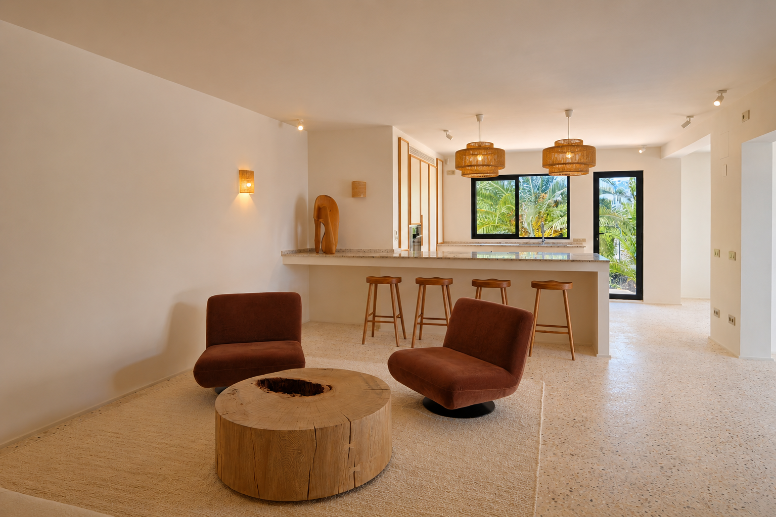Zona de estar de concepto abierto con dos sillones color óxido, una mesa de centro rústica de madera y suelo de terrazo claro. El espacio conecta con una barra iluminada por lámparas de mimbre y vistas a la vegetación.
