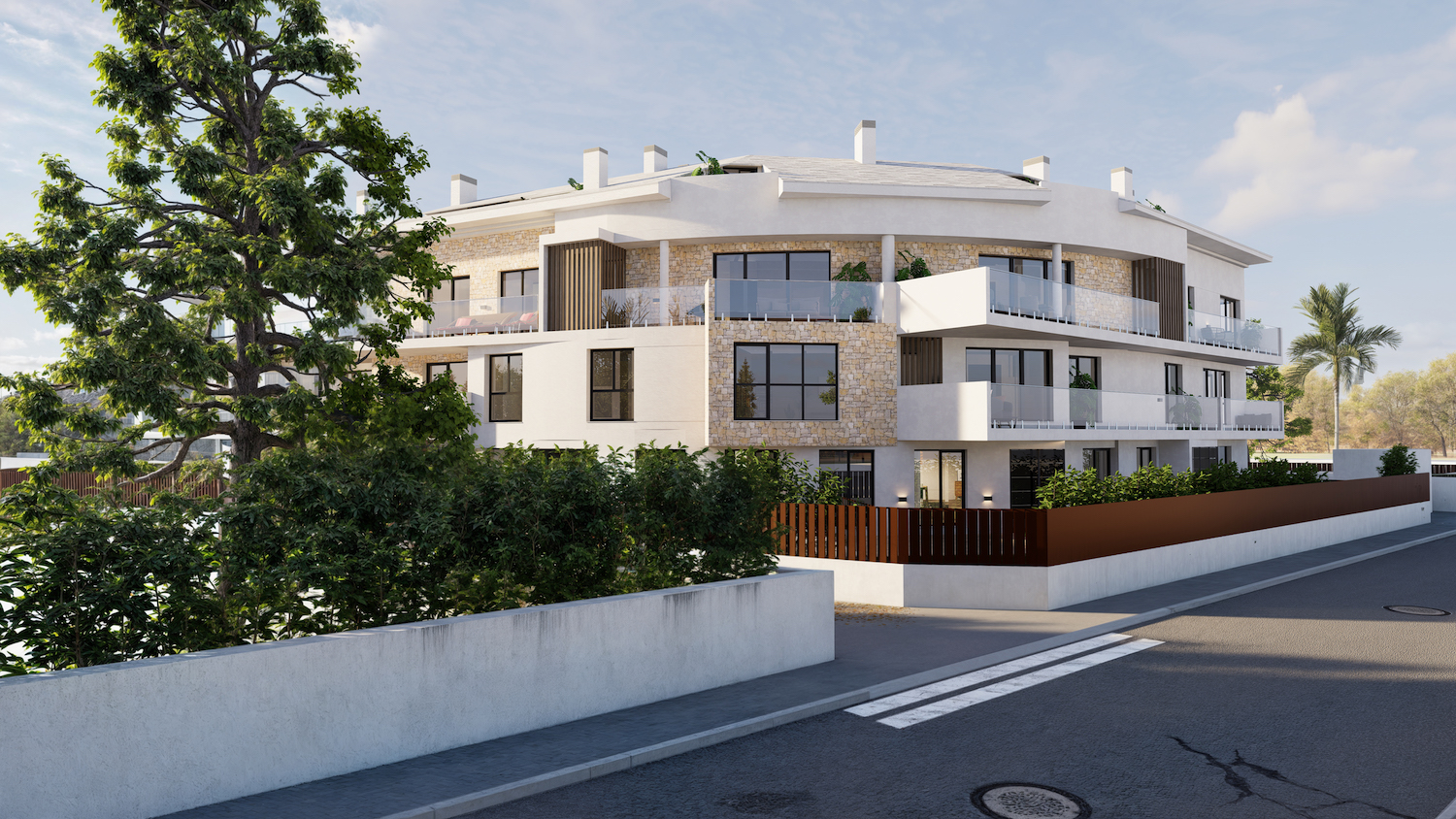 Edificio de apartamentos moderno con fachada curva, revestido de estuco blanco y piedra natural, con balcones acristalados. Vegetación mediterránea enmarca la propiedad desde la calle.