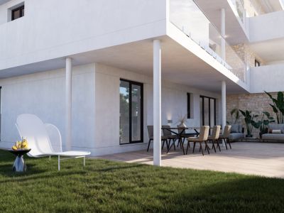 Amplia terraza en planta baja con tarima de madera clara, mobiliario de comedor y zona lounge, conectando con un cuidado césped que incluye una moderna tumbona blanca.