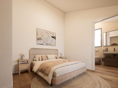 Dormitorio principal sereno con cabecero de ratán, mesitas de noche de madera clara y alfombra redonda de fibra natural. Se aprecia un baño moderno con tocador flotante.