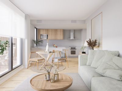 Salón-comedor de planta abierta con sofá verde claro, mesa de centro de madera y comedor con sillas de mimbre. Cocina moderna con armarios de madera clara y electrodomésticos integrados, bañada en luz natural.