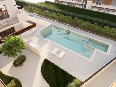 Vista de la piscina comunitaria con mosaicos celestes, escalones integrados y ducha exterior. La terraza pavimentada circundante incluye tumbonas blancas y un juego de comedor, complementada con áreas verdes cuidadas.