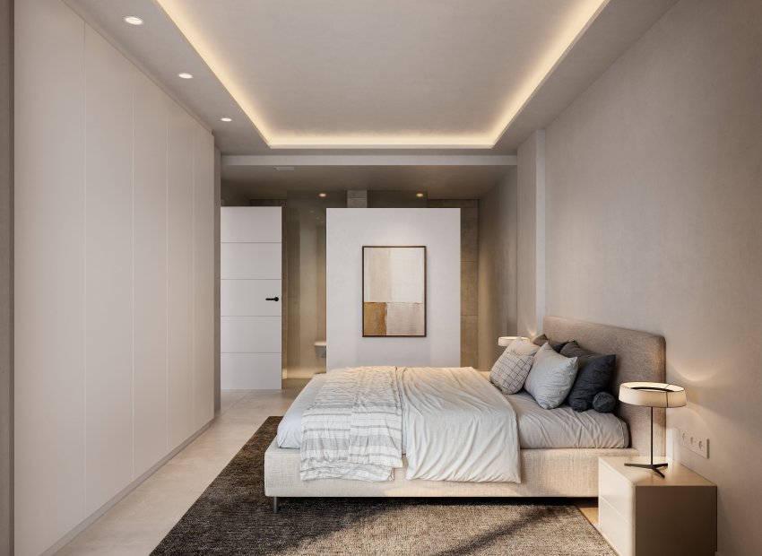 Dormitorio principal moderno con paleta neutra, armarios empotrados de suelo a techo y techo suspendido con iluminación LED ambiental. Una pared parcial divide el área de descanso del baño privado.