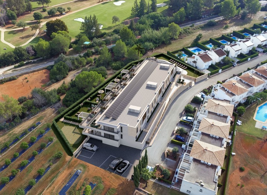 Vista aérea de un edificio moderno con techo solar y una amplia terraza ajardinada con pérgolas, asientos al aire libre y un putting green, junto a un campo de golf.