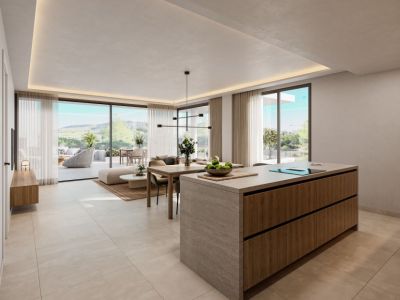 Espacio de vida diáfano moderno con isla de cocina de piedra y madera, comedor contiguo y salón luminoso. Grandes puertas correderas de cristal conectan con una terraza privada y vistas al paisaje verde.
