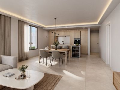 Espacio diáfano moderno con cocina de madera clara, electrodomésticos integrados y vinoteca. Comedor con lámpara lineal y sala de estar con sofá, bajo iluminación natural y luz indirecta en el techo.