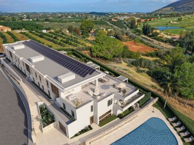 Vista aérea de una residencia de lujo moderna con amplias terrazas en la azotea, áreas de salón y comedor, piscina de azulejos azules y paneles solares. Se enclava junto a un campo de golf y huertos en terrazas.