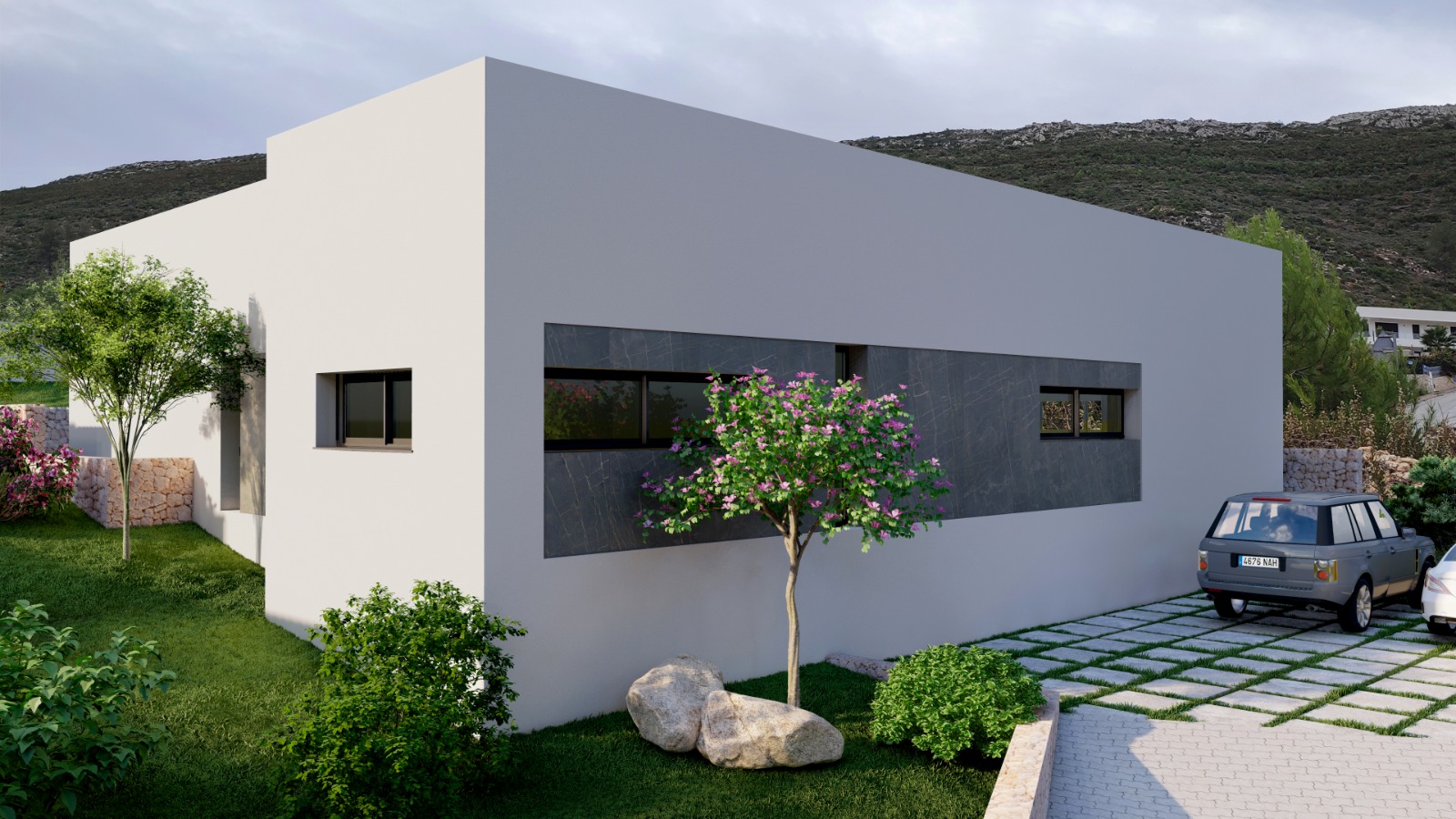 Exterior de villa moderna con fachada blanca y detalles en paneles de piedra oscura. Jardín con césped, árboles y entrada adoquinada con césped, en un entorno montañoso.