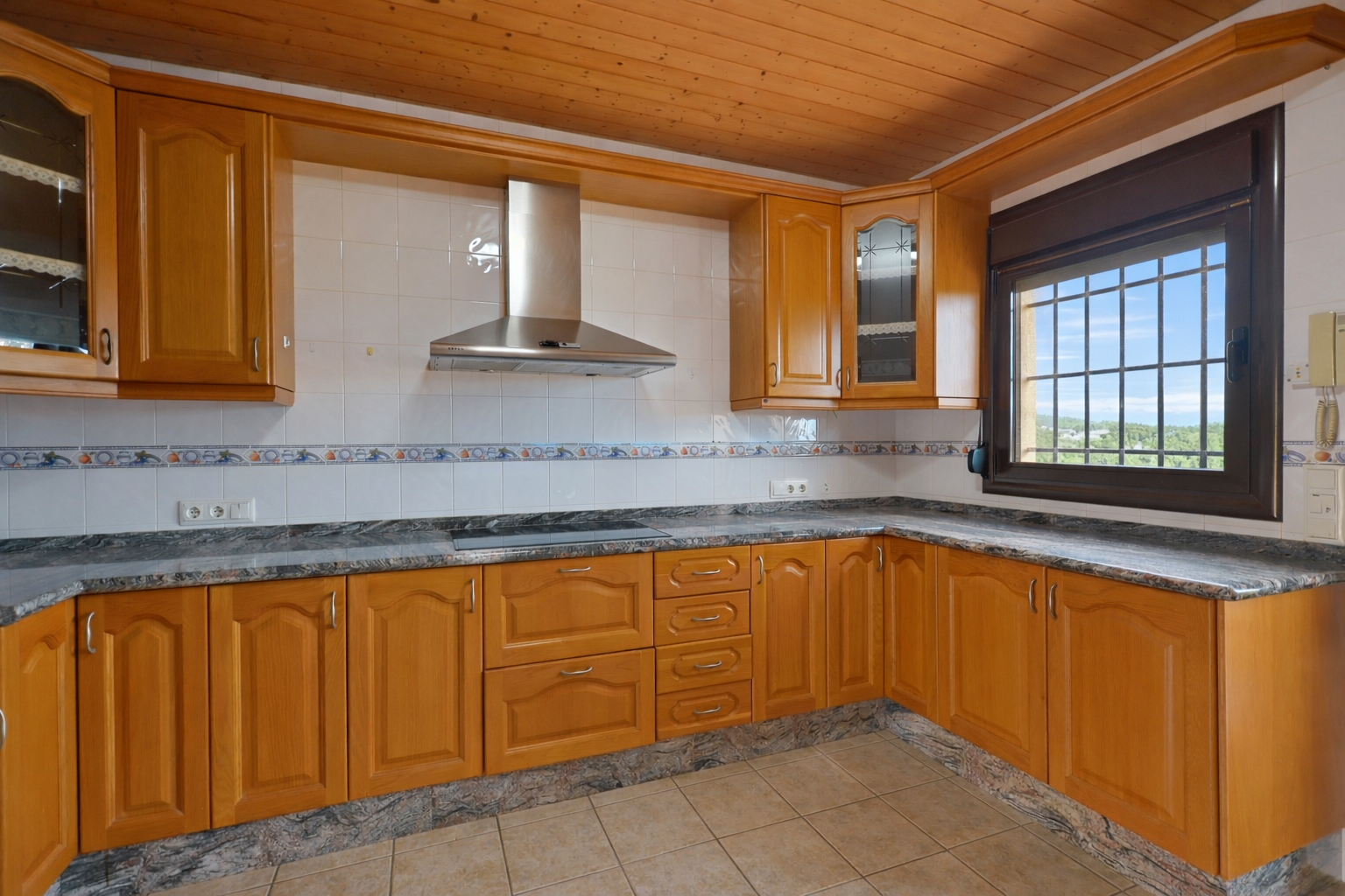 Cocina equipada con mobiliario de madera, encimeras de granito y techo de lamas de madera. Ventana con rejas ofrece vistas al exterior. Cocina equipada con mobiliario de madera, encimeras de granito y techo de lamas de madera. Ventana con rejas ofrece vistas al exterior.