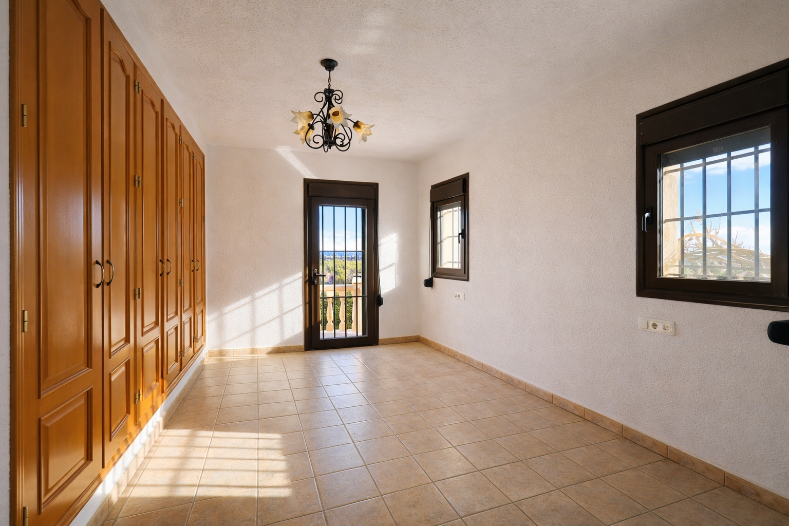 Habitación luminosa con armarios empotrados de madera, suelo de baldosas claras y paredes texturizadas. Dispone de acceso a balcón con vistas al paisaje y ventanas con rejas. Habitación luminosa con armarios empotrados de madera, suelo de baldosas claras y paredes texturizadas. Dispone de acceso a balcón con vistas al paisaje y ventanas con rejas.