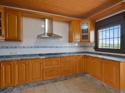 Cocina equipada con mobiliario de madera, encimeras de granito y techo de lamas de madera. Ventana con rejas ofrece vistas al exterior.