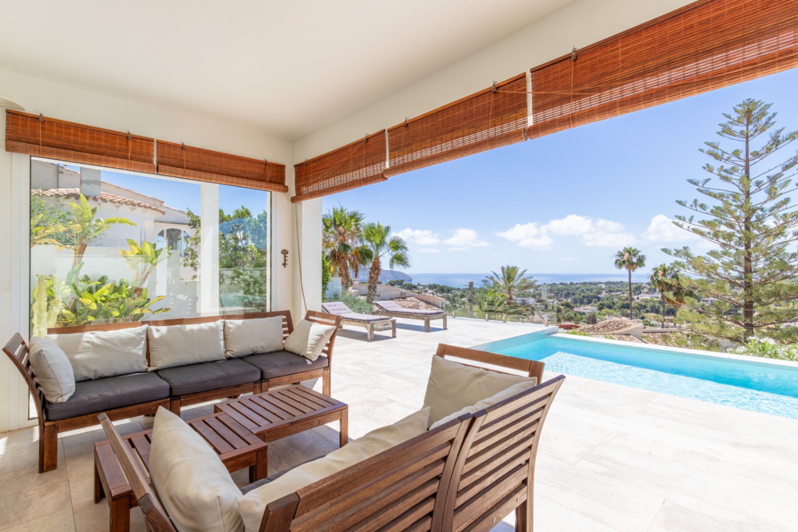 Amplia terraza cubierta con mobiliario de madera, suelo de baldosas claras y piscina infinita, ofreciendo vistas panorámicas al mar Mediterráneo. Amplia terraza cubierta con mobiliario de madera, suelo de baldosas claras y piscina infinita, ofreciendo vistas panorámicas al mar Mediterráneo.