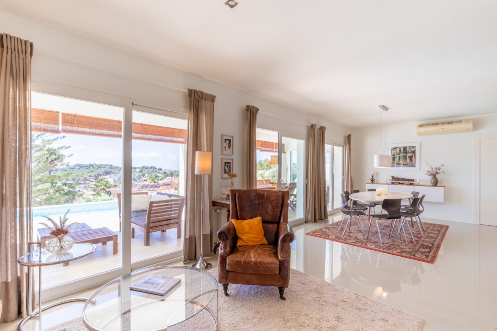 Salón-comedor diáfano con amplios ventanales que conectan directamente con la terraza, piscina y vistas al paisaje. Suelos de gres blanco y mobiliario contemporáneo. Salón-comedor diáfano con amplios ventanales que conectan directamente con la terraza, piscina y vistas al paisaje. Suelos de gres blanco y mobiliario contemporáneo.