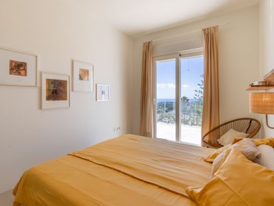 Dormitorio luminoso con cama doble y acceso directo a una terraza. Ofrece vistas panorámicas al mar Mediterráneo a través de una gran puerta corredera.