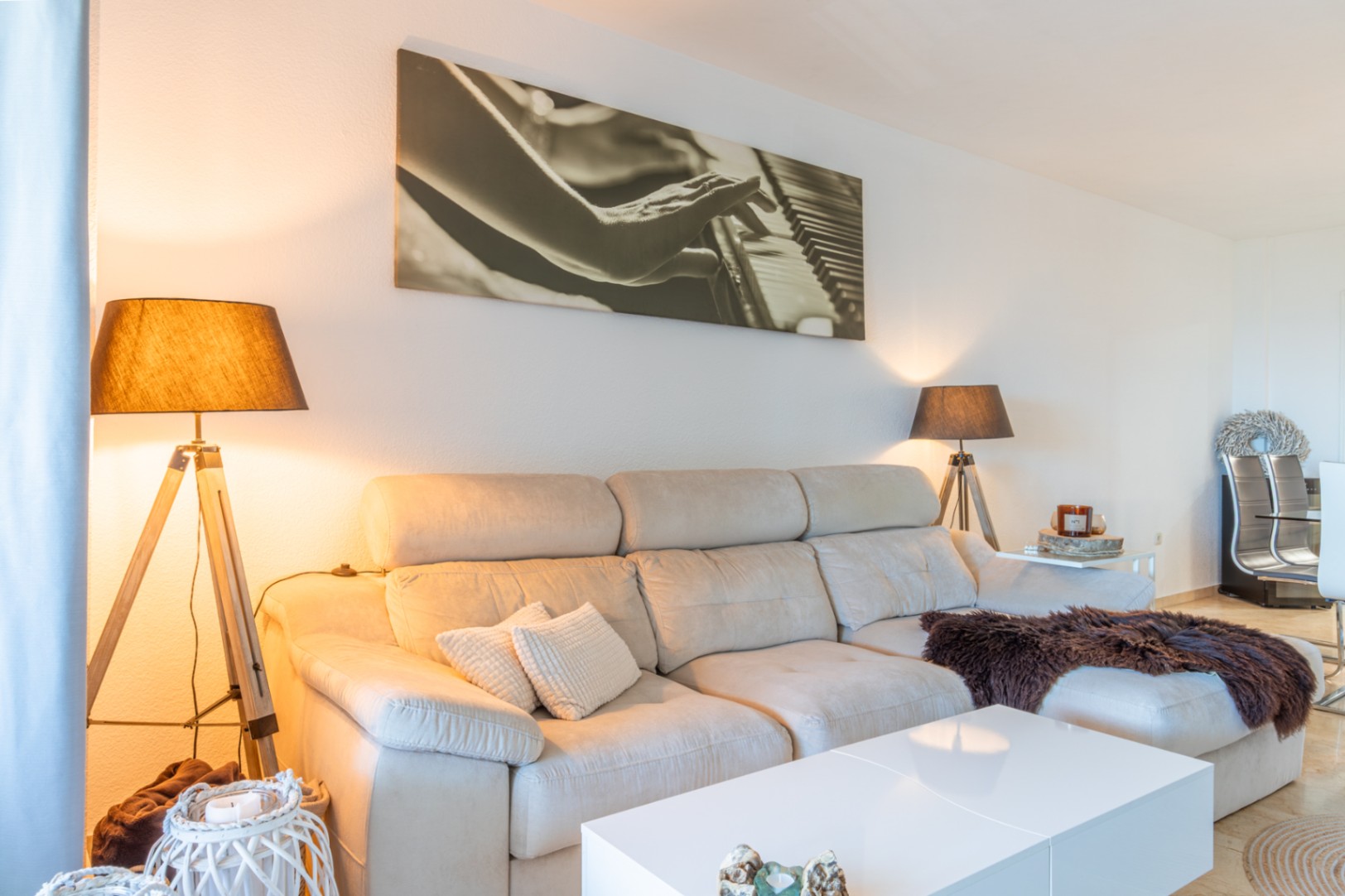 Salón con sofá seccional claro, mesa de centro blanca y dos lámparas de pie de diseño. Un gran cuadro de piano decora la pared, creando un ambiente acogedor. Salón con sofá seccional claro, mesa de centro blanca y dos lámparas de pie de diseño. Un gran cuadro de piano decora la pared, creando un ambiente acogedor.