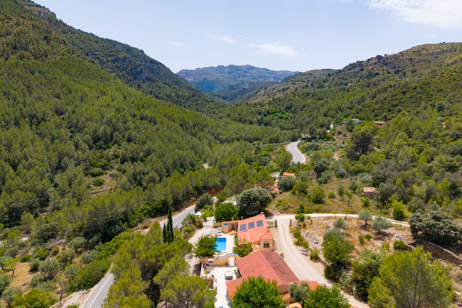 Vista aérea de la finca con dos viviendas, piscina y paneles solares, enclavada en un valle montañoso con densa vegetación mediterránea. Vista aérea de la finca con dos viviendas, piscina y paneles solares, enclavada en un valle montañoso con densa vegetación mediterránea.