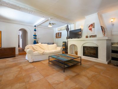 Acogedor salón con chimenea de ladrillo blanco y televisión, un cómodo sofá y una mesa de centro única con tapa de madera reciclada sobre baldosas de terracota.