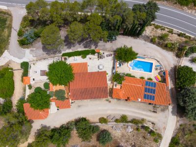 Vista aérea de la finca con dos viviendas, piscina rectangular, paneles solares en uno de los tejados de teja y amplias zonas exteriores.