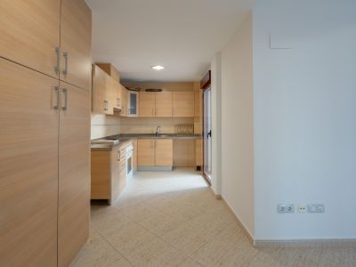 Cocina equipada con armarios de madera clara, encimeras de granito y suelo de baldosas. Incluye una puerta acristalada que da a un patio.