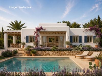 La fachada blanca de la villa, adornada con buganvillas y persianas azules, domina una piscina rectangular. Un muro de piedra y jardín mediterráneo con lavanda enmarcan el tranquilo espacio exterior.