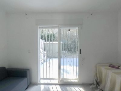 Amplia estancia con puertas correderas de cristal y rejas de seguridad, ofreciendo acceso directo al jardín privado e iluminada por luz natural sobre el suelo claro.