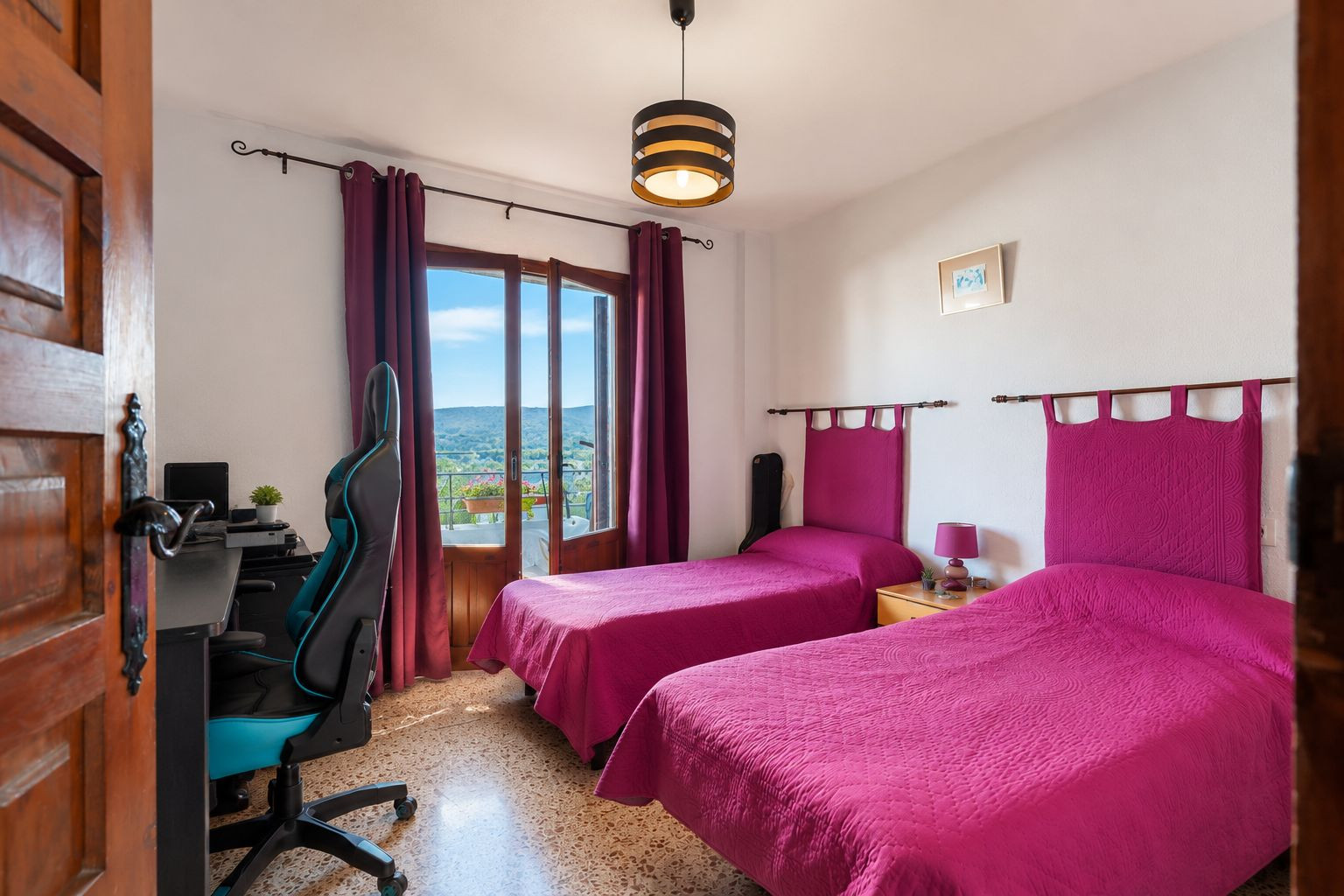 Luminoso dormitorio con dos camas individuales, cabeceros fucsia y acceso directo a balcón con vistas a las montañas. Incluye zona de escritorio y suelo de terrazo. Luminoso dormitorio con dos camas individuales, cabeceros fucsia y acceso directo a balcón con vistas a las montañas. Incluye zona de escritorio y suelo de terrazo.