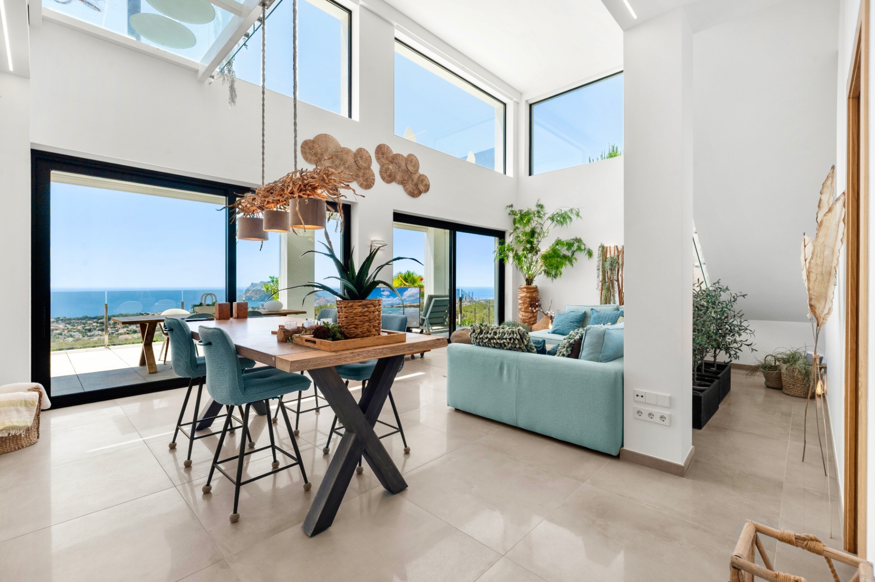 Amplio salón-comedor de planta abierta con techos altos, grandes ventanales y una lámpara de ramas única. Disfrute de vistas panorámicas al mar, la costa y el Peñón de Ifach desde este luminoso interior. Amplio salón-comedor de planta abierta con techos altos, grandes ventanales y una lámpara de ramas única. Disfrute de vistas panorámicas al mar, la costa y el Peñón de Ifach desde este luminoso interior.