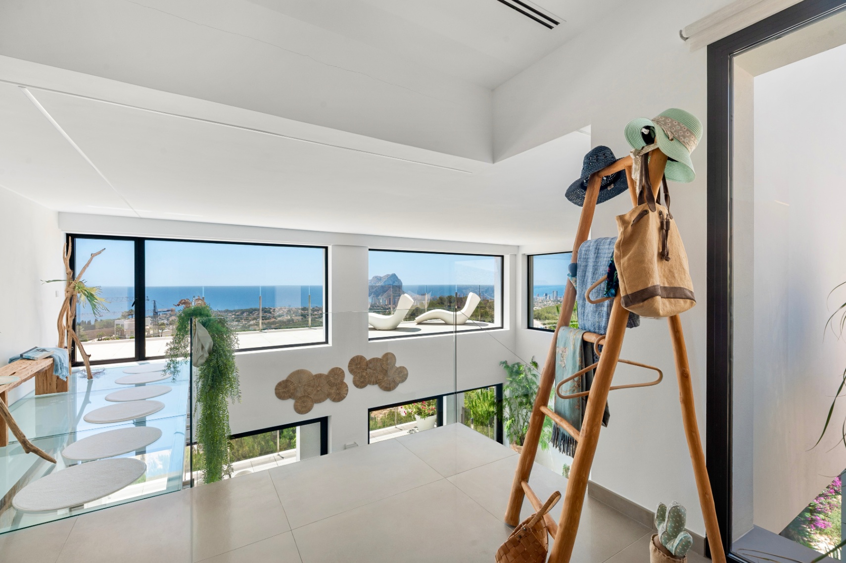 Planta superior con suelo de gres claro y barandilla de cristal, ofreciendo vistas panorámicas al mar y al Peñon de Ifach. Incluye una pasarela de cristal con peldaños ovalados y un perchero de madera. Planta superior con suelo de gres claro y barandilla de cristal, ofreciendo vistas panorámicas al mar y al Peñon de Ifach. Incluye una pasarela de cristal con peldaños ovalados y un perchero de madera.