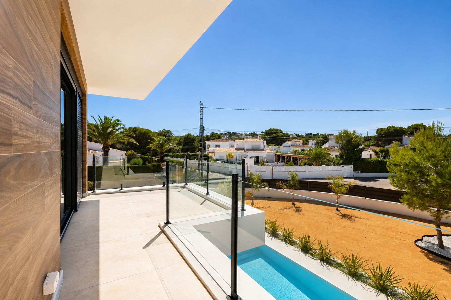 Terraza superior con suelo porcelánico claro, barandilla de cristal y vistas a la urbanización. Incluye una pequeña piscina lineal y un muro exterior con revestimiento de madera.