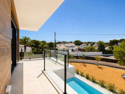 Terraza superior con suelo porcelánico claro, barandilla de cristal y vistas a la urbanización. Incluye una pequeña piscina lineal y un muro exterior con revestimiento de madera.