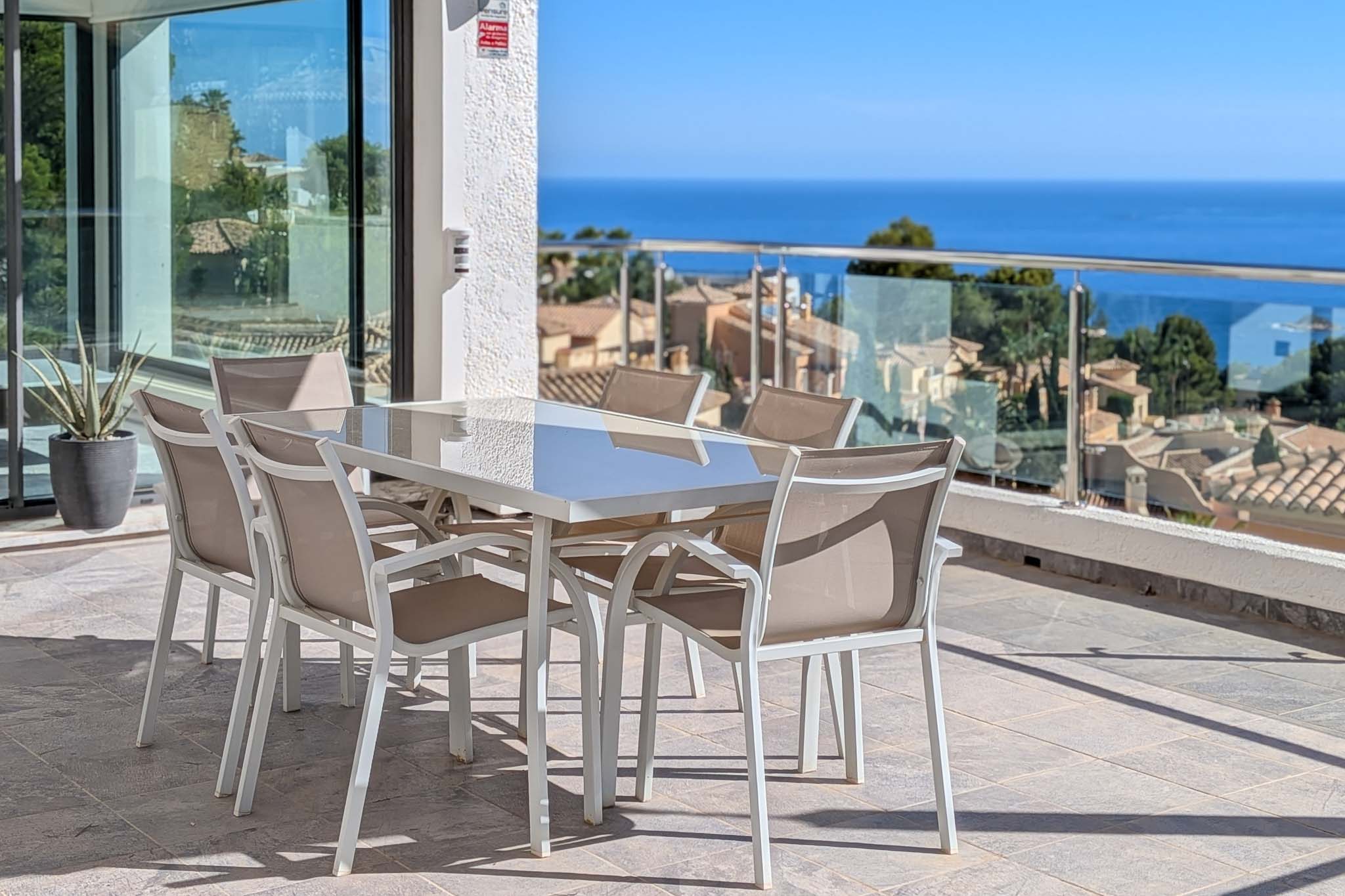 Amplia terraza exterior con mesa de comedor y sillas, ofreciendo vistas panorámicas al mar Mediterráneo y los tejados de Altea Hills. Puertas correderas de cristal conectan con el interior. Amplia terraza exterior con mesa de comedor y sillas, ofreciendo vistas panorámicas al mar Mediterráneo y los tejados de Altea Hills. Puertas correderas de cristal conectan con el interior.