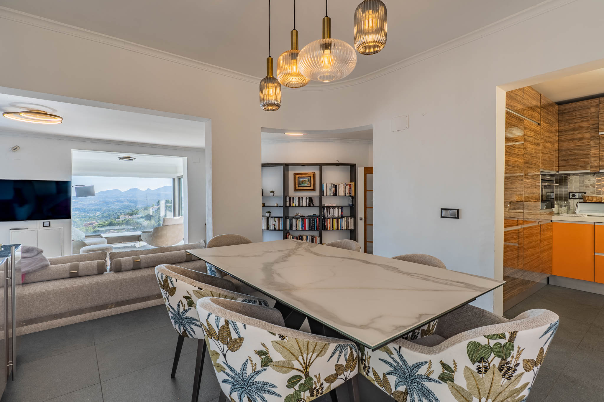 Comedor de diseño con mesa de efecto mármol y sillas tapizadas, iluminado por lámparas colgantes modernas. Conecta con el salón, ofreciendo vistas panorámicas a la montaña. Comedor de diseño con mesa de efecto mármol y sillas tapizadas, iluminado por lámparas colgantes modernas. Conecta con el salón, ofreciendo vistas panorámicas a la montaña.
