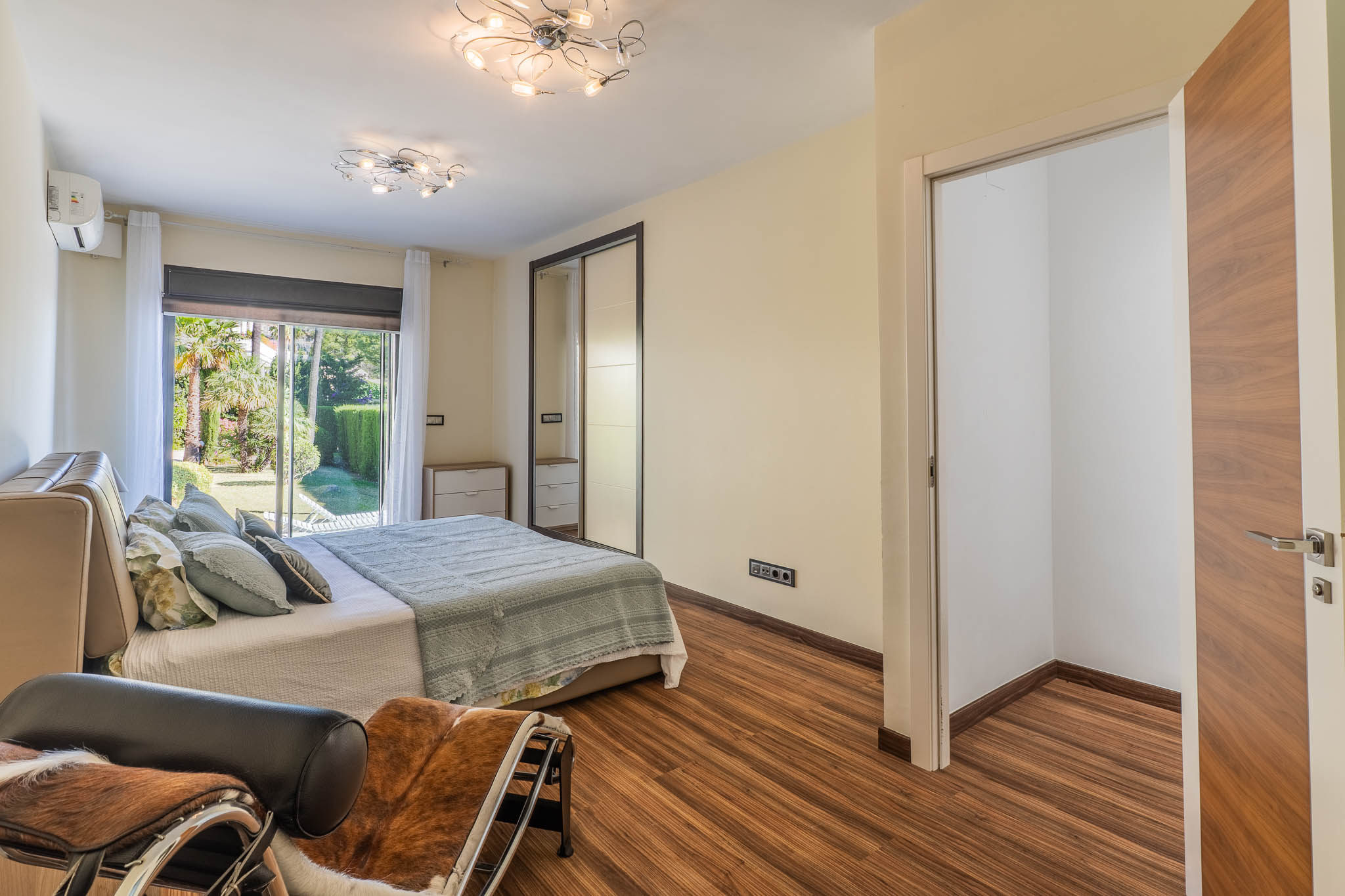 Dormitorio principal con acceso directo al jardín a través de puertas correderas de cristal, suelo laminado y armario empotrado con puertas de espejo. Incluye un espacio de vestidor abierto. Dormitorio principal con acceso directo al jardín a través de puertas correderas de cristal, suelo laminado y armario empotrado con puertas de espejo. Incluye un espacio de vestidor abierto.