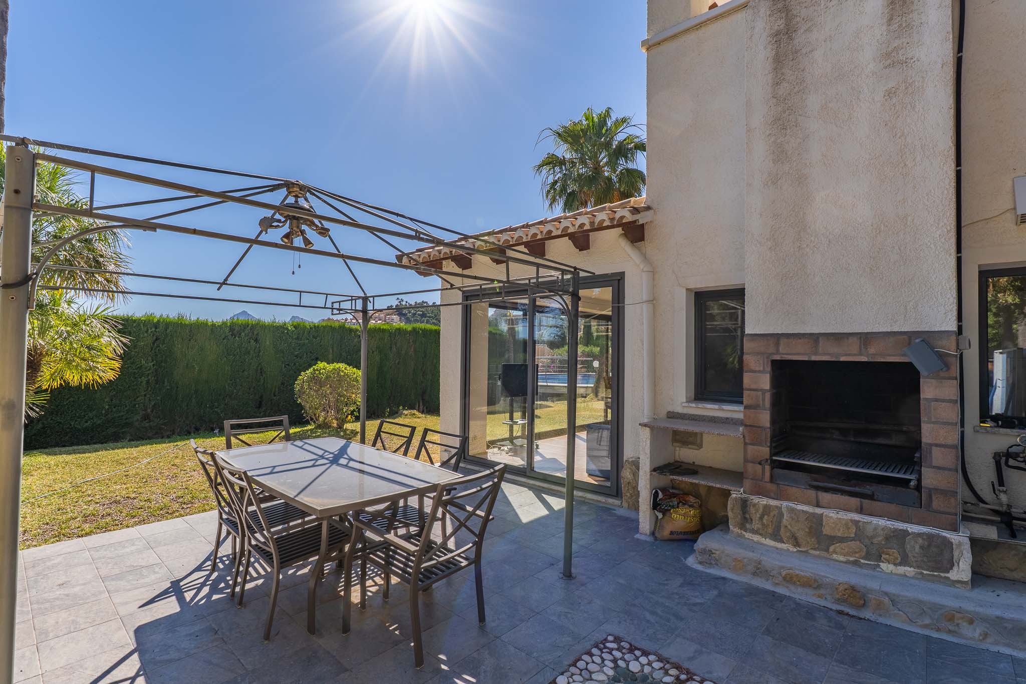 Patio exterior con suelo de gres oscuro, pérgola metálica y mesa de comedor. Incluye una barbacoa de obra con ladrillo y piedra, y acceso a través de puertas correderas de cristal. Patio exterior con suelo de gres oscuro, pérgola metálica y mesa de comedor. Incluye una barbacoa de obra con ladrillo y piedra, y acceso a través de puertas correderas de cristal.