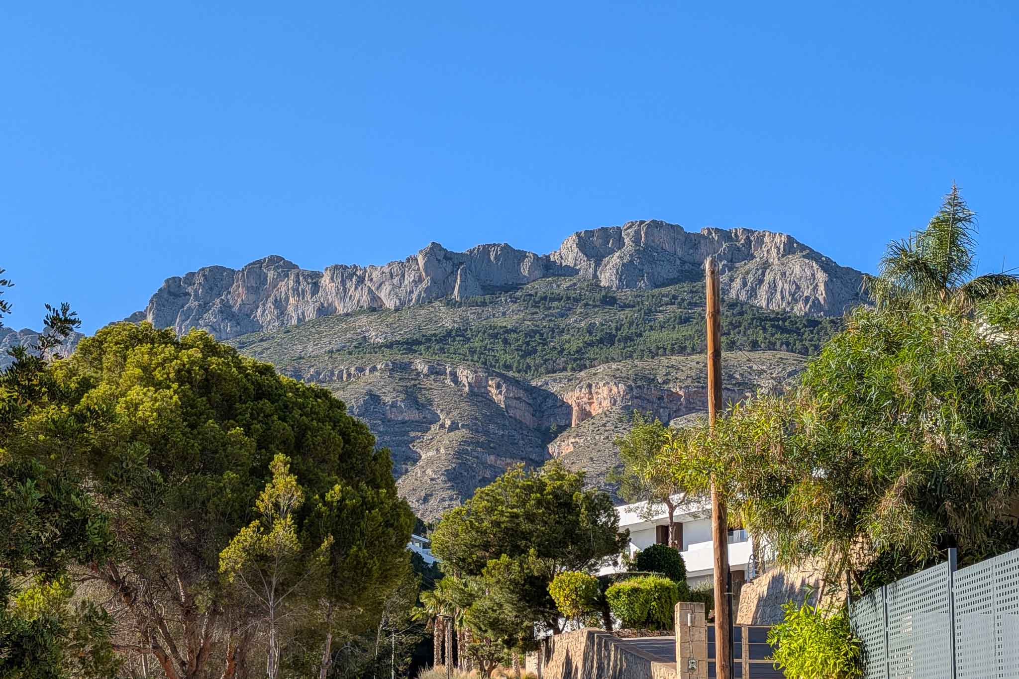 Vista de la majestuosa Sierra de Bernia, con sus picos rocosos y laderas verdes, enmarcada por la exuberante vegetación mediterránea que rodea la propiedad. Vista de la majestuosa Sierra de Bernia, con sus picos rocosos y laderas verdes, enmarcada por la exuberante vegetación mediterránea que rodea la propiedad.