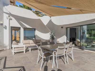 Amplia terraza exterior con suelo de gres, mobiliario de comedor y zona lounge bajo toldo retráctil. Grandes ventanales conectan con el interior.
