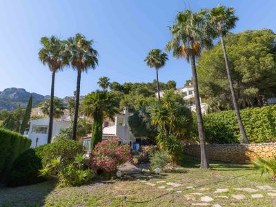 El jardín llano y paisajístico de la propiedad cuenta con un sendero de piedra, palmeras maduras, buganvillas vibrantes y agaves, con un telón de fondo de colinas verdes y montañas lejanas.