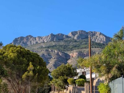 Vista de la majestuosa Sierra de Bernia, con sus picos rocosos y laderas verdes, enmarcada por la exuberante vegetación mediterránea que rodea la propiedad.