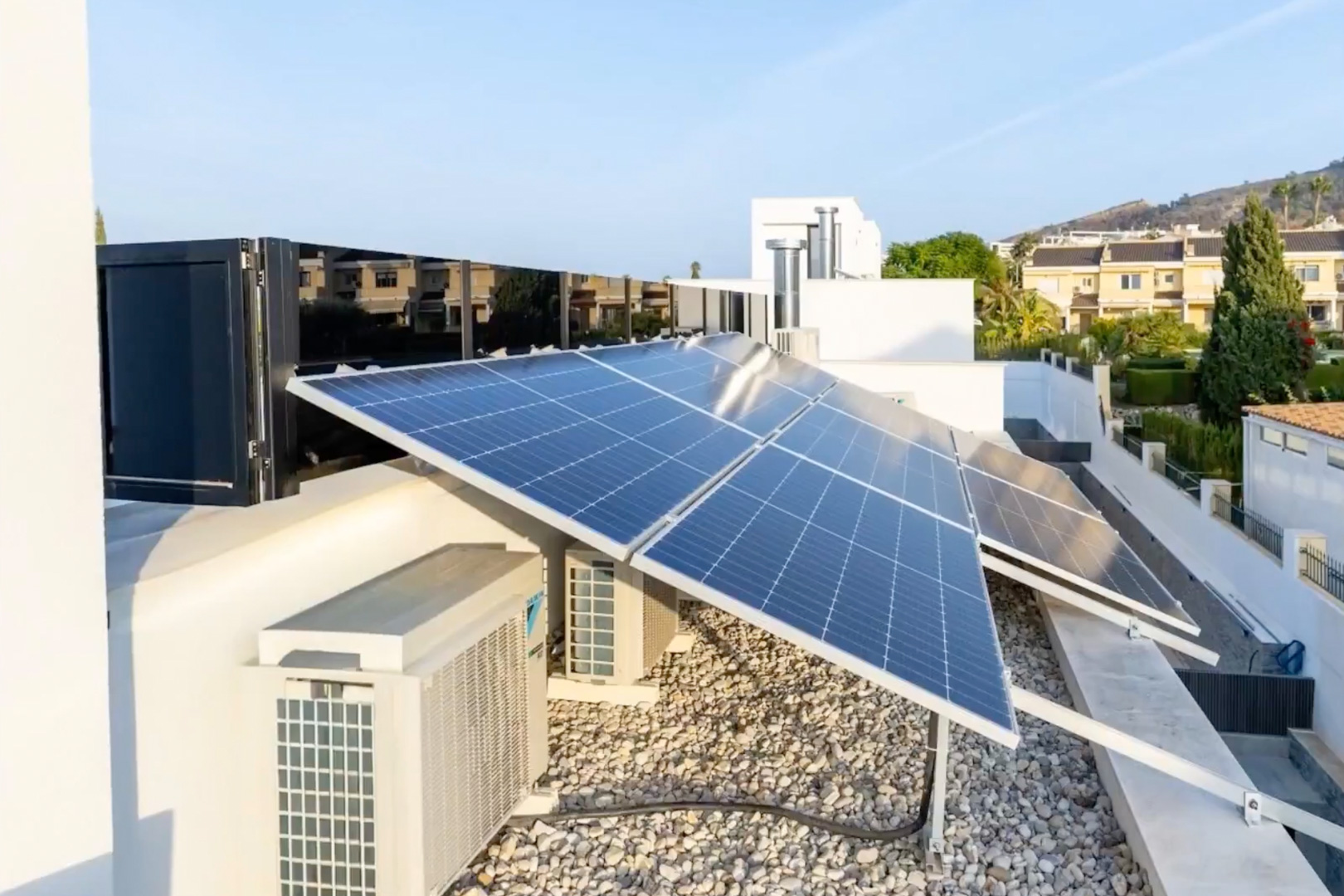 Amplio sistema de paneles solares fotovoltaicos en cubierta. Unidades de climatización y una superficie de grava clara completan esta instalación de alta eficiencia. Amplio sistema de paneles solares fotovoltaicos en cubierta. Unidades de climatización y una superficie de grava clara completan esta instalación de alta eficiencia.
