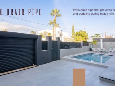 Amplio patio exterior con piscina, suelo de baldosas grises y moderno portón de garaje. Incluye sistema de drenaje para evitar encharcamientos.