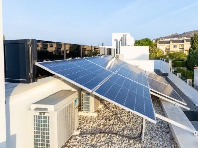 Amplio sistema de paneles solares fotovoltaicos en cubierta. Unidades de climatización y una superficie de grava clara completan esta instalación de alta eficiencia.