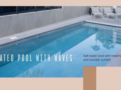 Piscina climatizada de agua salada con sistema contracorriente y escalones, rodeada de baldosas grises y solárium con tumbonas.